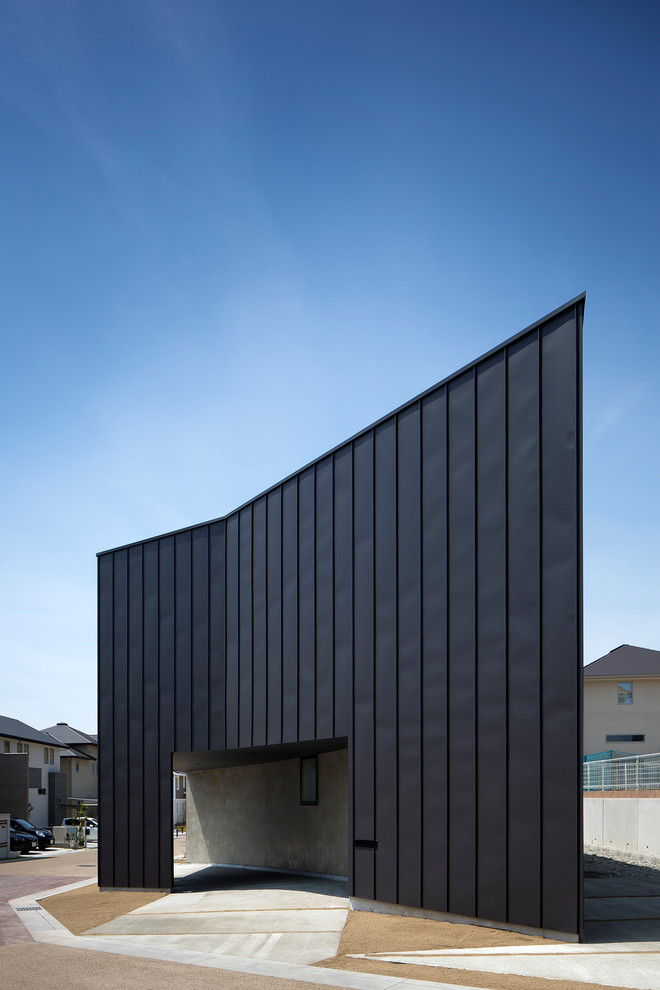 Cette photo montre une façade de maison métallique et noire moderne de taille moyenne et à un étage avec un toit en appentis et un toit en métal.