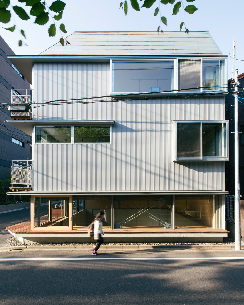 Mittelgroßes, Zweistöckiges Modernes Einfamilienhaus mit Mix-Fassade, grauer Fassadenfarbe, Walmdach und Blechdach in Tokio