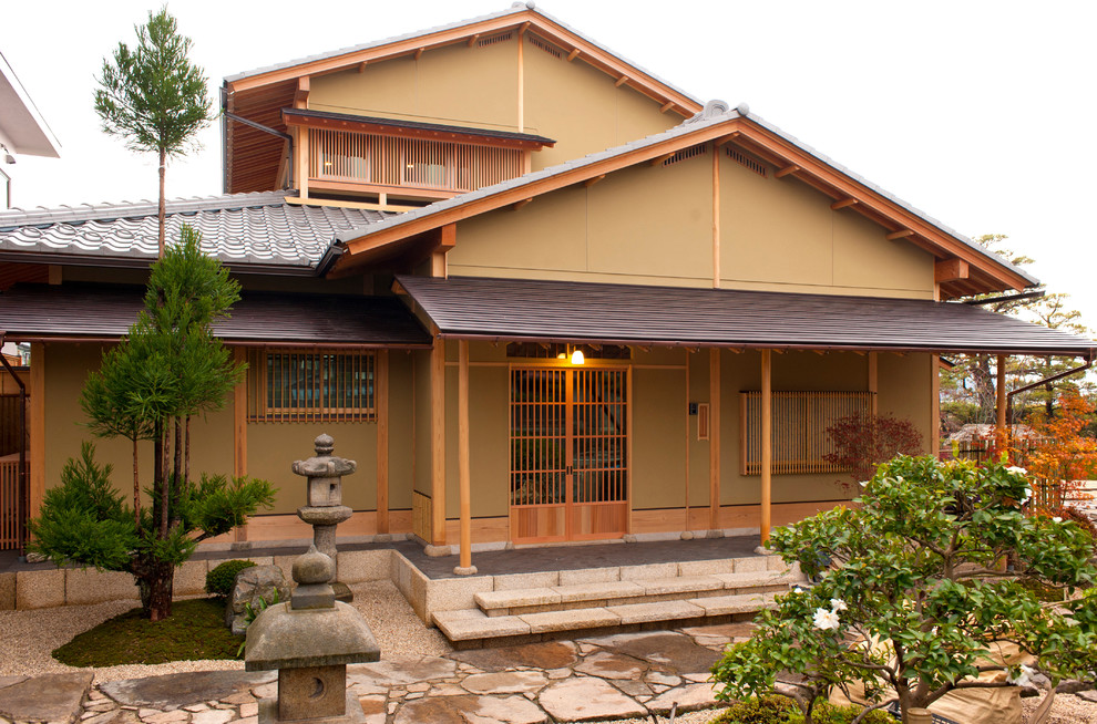 Idée de décoration pour une façade de maison beige asiatique à un étage avec un toit à deux pans.