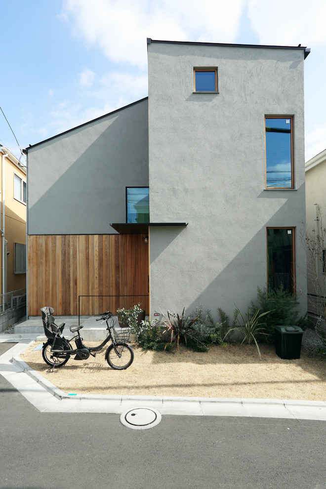 Inspiration pour une façade de maison grise asiatique en stuc de taille moyenne et à un étage avec un toit en appentis et un toit en métal.