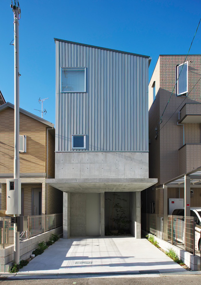 Imagen de fachada de casa gris urbana de tamaño medio de tres plantas con revestimiento de hormigón, tejado de un solo tendido y tejado de metal