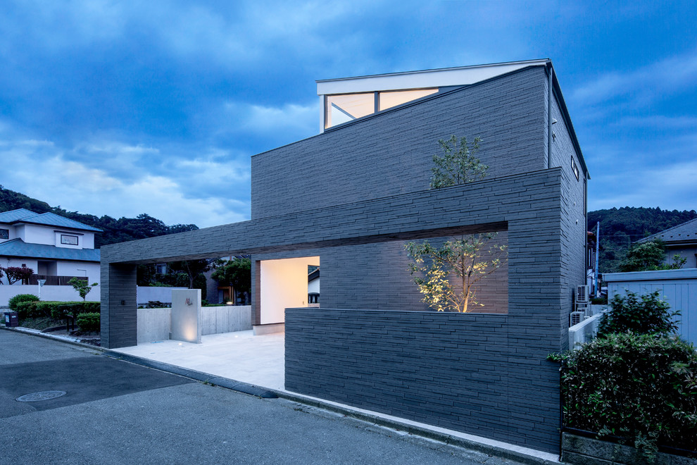 На фото: двухэтажный, серый частный загородный дом среднего размера в стиле модернизм с облицовкой из камня, односкатной крышей и металлической крышей с