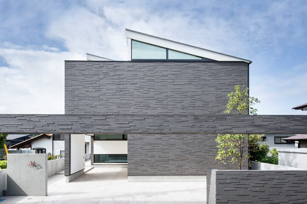 Идея дизайна: двухэтажный, серый частный загородный дом среднего размера в стиле модернизм с облицовкой из камня, односкатной крышей и металлической крышей
