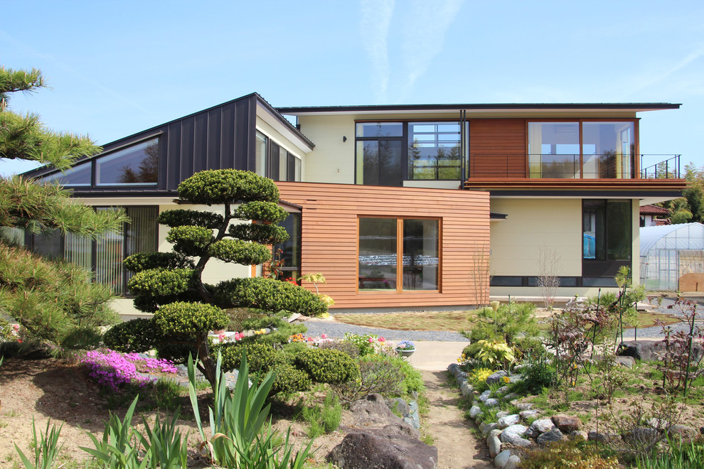 Diseño de fachada de casa multicolor de estilo zen grande a niveles con revestimiento de madera, tejado de un solo tendido y tejado de metal
