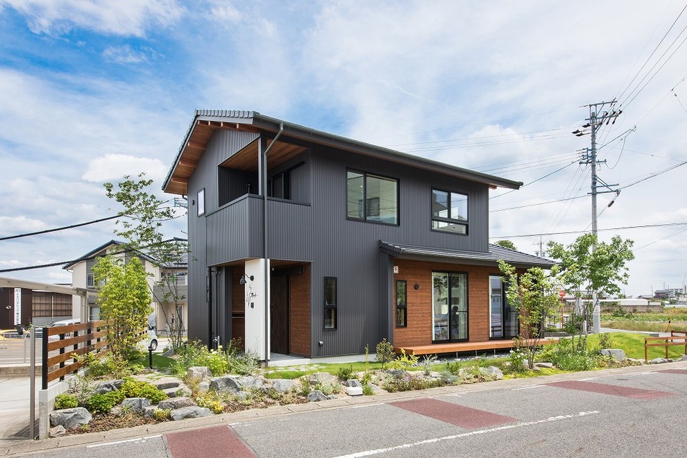 Ejemplo de fachada de casa negra urbana de tamaño medio de dos plantas con revestimiento de metal, tejado a dos aguas y tejado de teja de barro