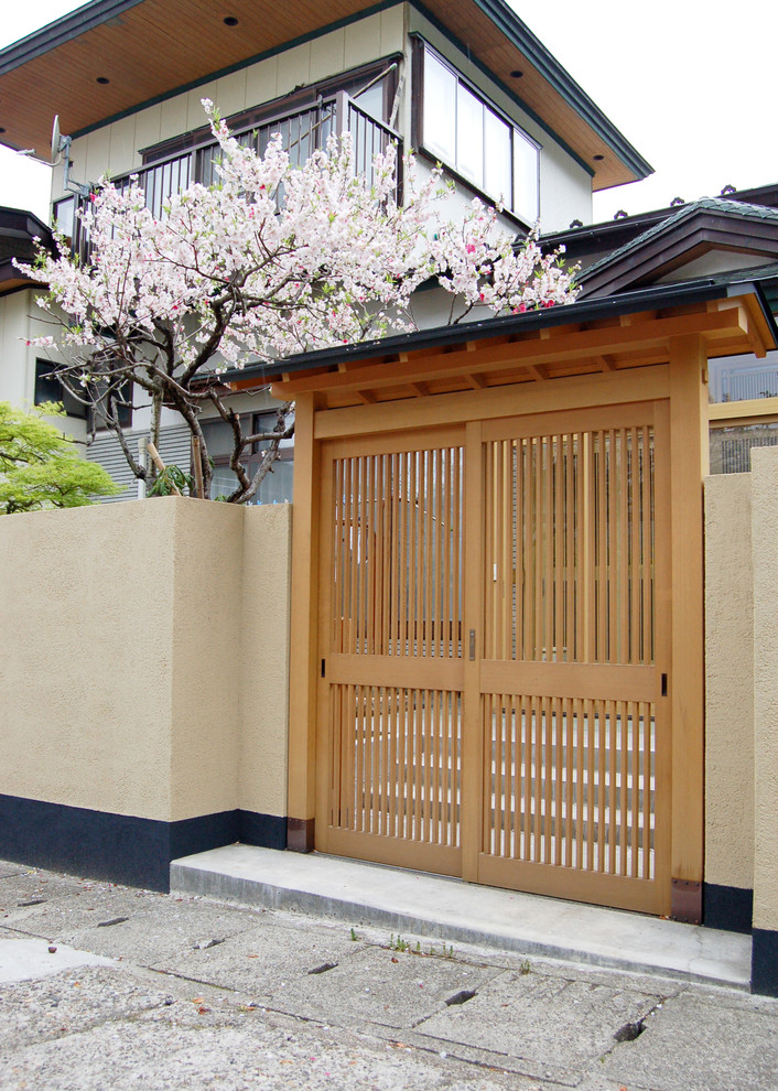 Ispirazione per la facciata di una casa beige etnica a due piani con rivestimento in legno