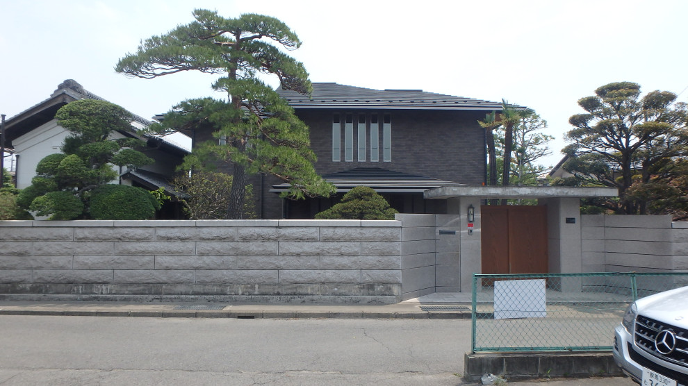 Imagen de fachada de casa marrón minimalista grande de dos plantas con tejado a cuatro aguas y tejado de metal
