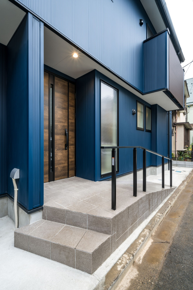 Cette image montre une façade de maison bleue urbaine à un étage avec un revêtement mixte, un toit à deux pans et un toit mixte.