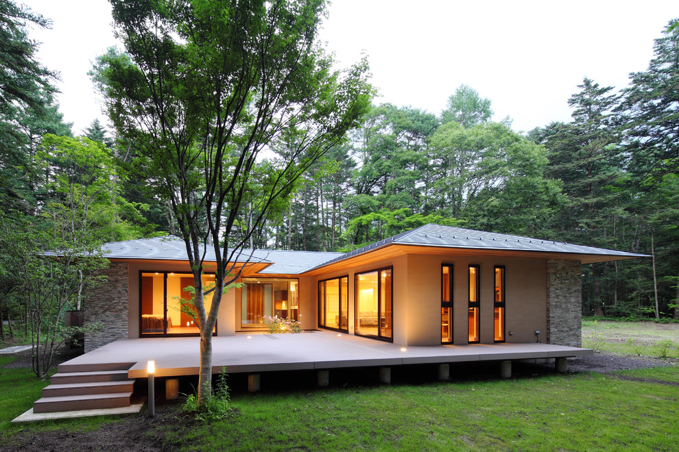 Diseño de fachada de casa beige asiática de tamaño medio de una planta con revestimiento de piedra, tejado a cuatro aguas y tejado de metal