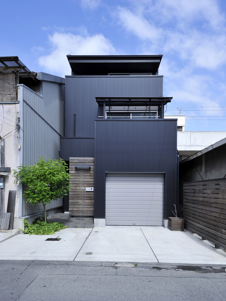Esempio della facciata di una casa nera contemporanea a tre piani con rivestimento in metallo e copertura in metallo o lamiera