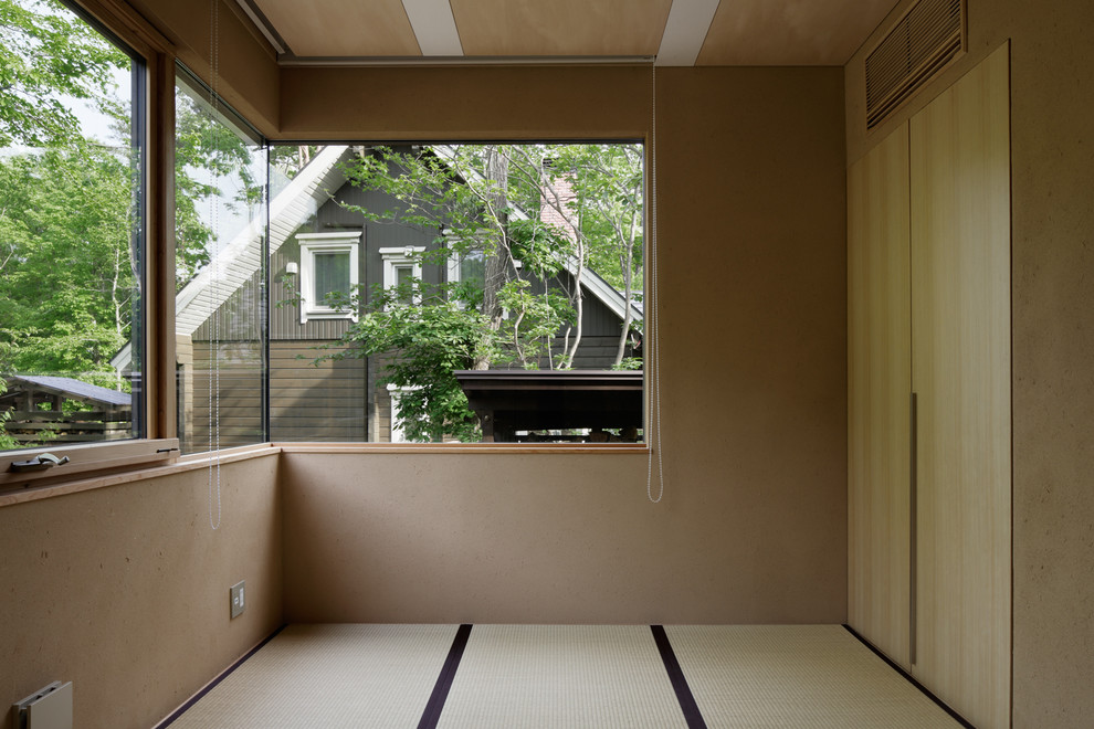 Modelo de habitación de invitados de estilo zen con paredes marrones, tatami y suelo verde
