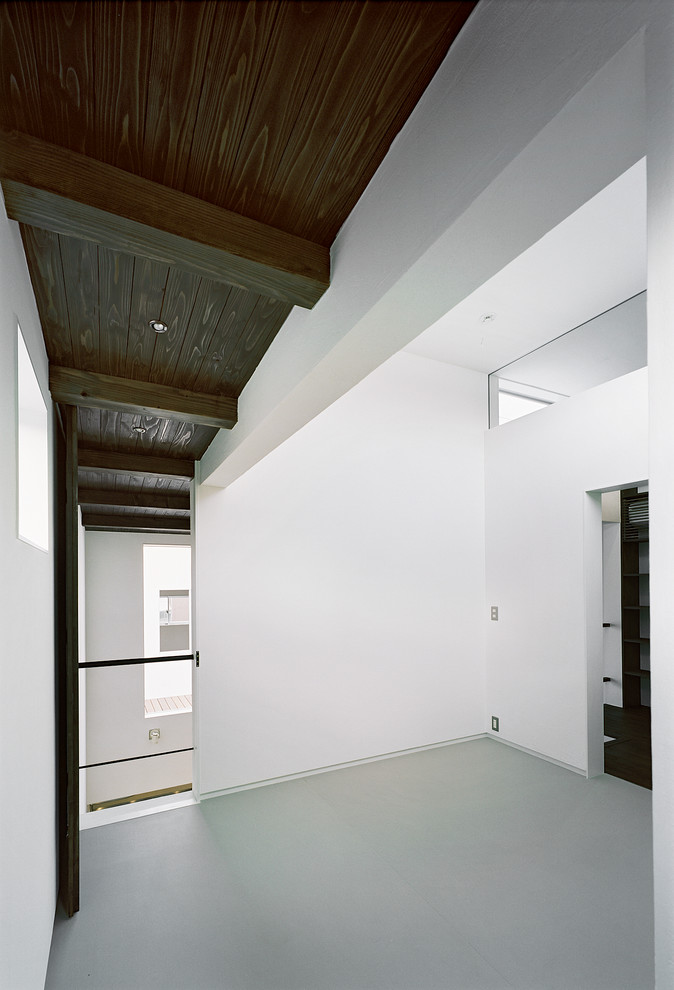 Imagen de habitación de invitados minimalista sin chimenea con paredes blancas, suelo de linóleo y suelo gris