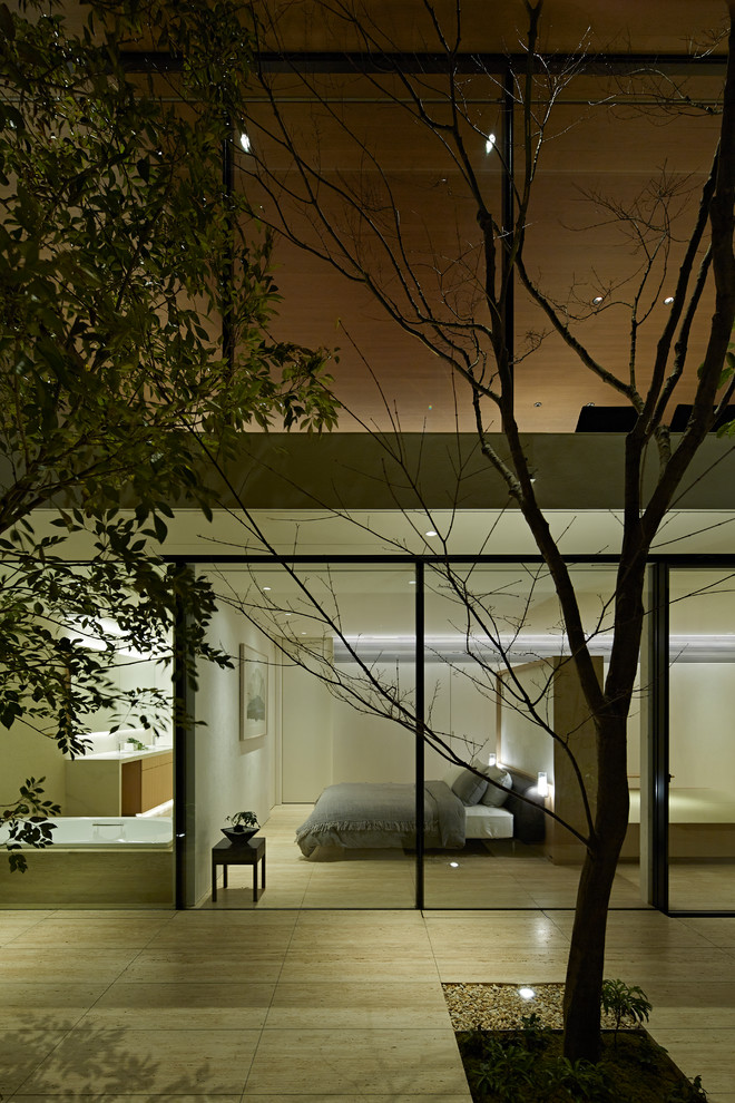 На фото: хозяйская спальня в стиле модернизм с белыми стенами, полом из травертина и бежевым полом