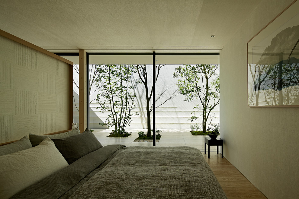 На фото: хозяйская спальня в стиле модернизм с белыми стенами, полом из травертина и бежевым полом с