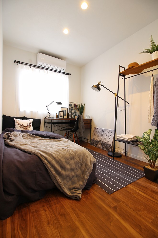Foto di una piccola camera da letto nordica con pareti bianche, pavimento in legno massello medio e pavimento marrone