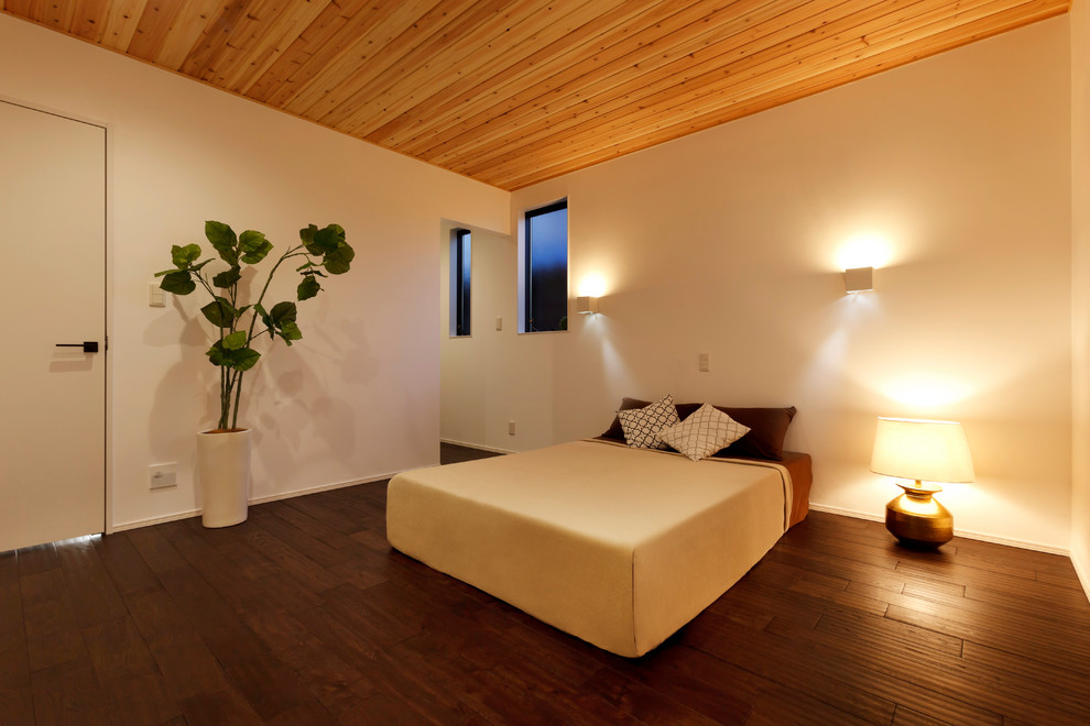 Foto de dormitorio principal moderno con paredes blancas, suelo de madera oscura y suelo marrón