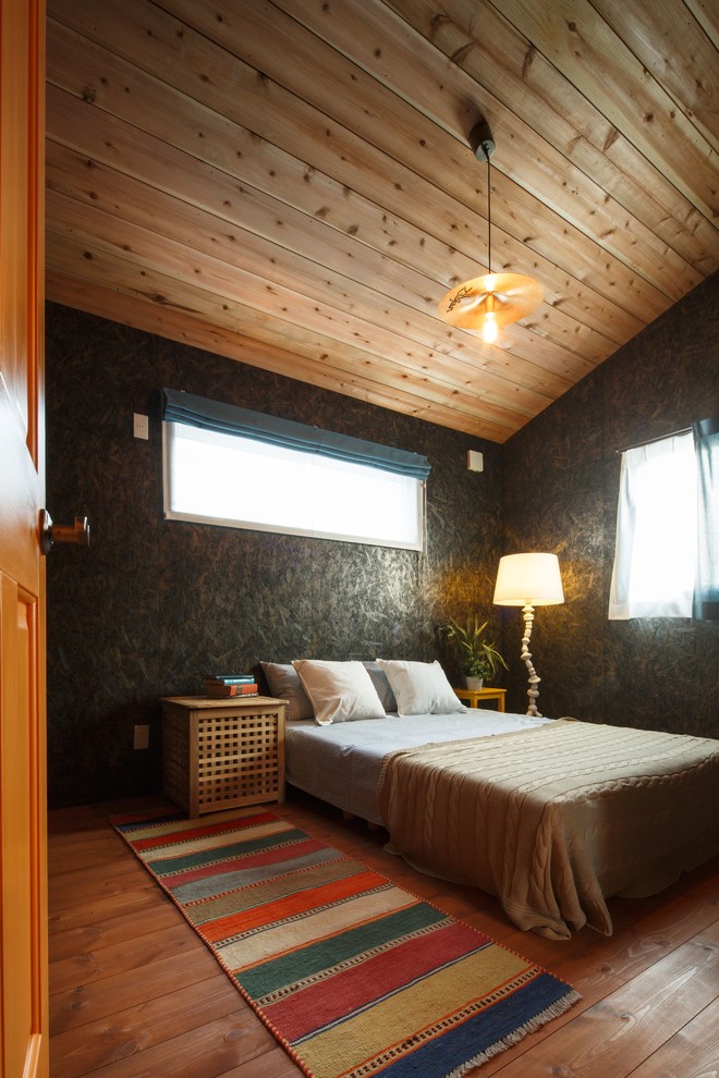 Immagine di una camera da letto etnica con pareti nere, pavimento in legno massello medio e pavimento marrone