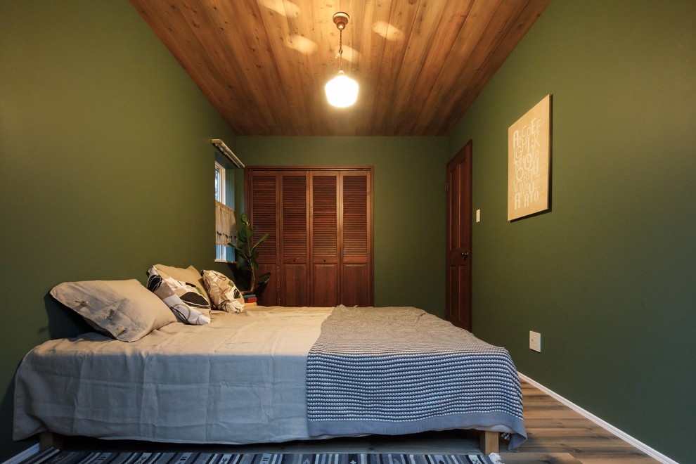Immagine di una camera da letto industriale con pareti verdi, pavimento in legno massello medio e pavimento marrone
