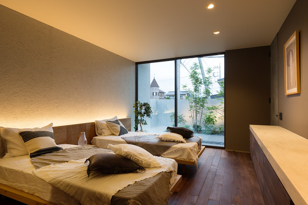 Idée de décoration pour une chambre parentale minimaliste de taille moyenne avec parquet foncé, un sol marron et un mur gris.