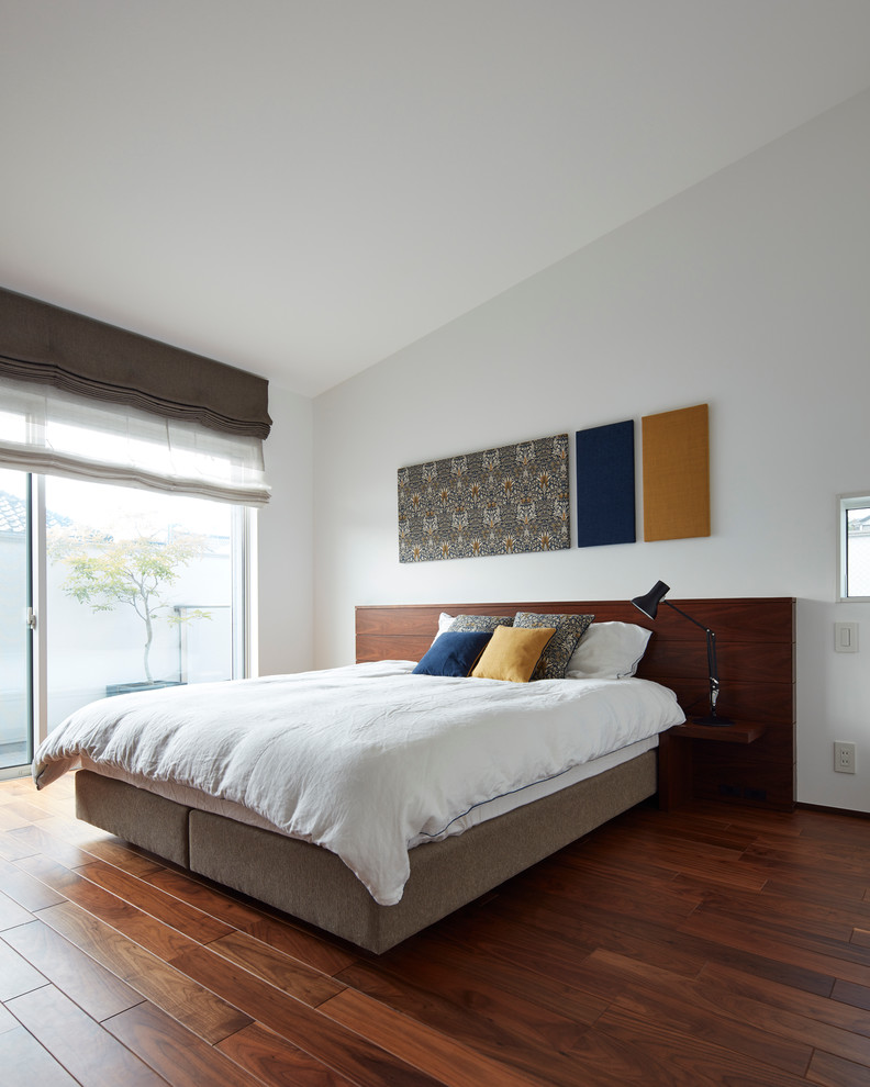 Immagine di una camera da letto design con pareti bianche, parquet scuro e nessun camino