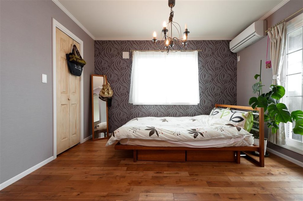 Diseño de dormitorio bohemio con paredes grises, suelo de madera en tonos medios y suelo marrón
