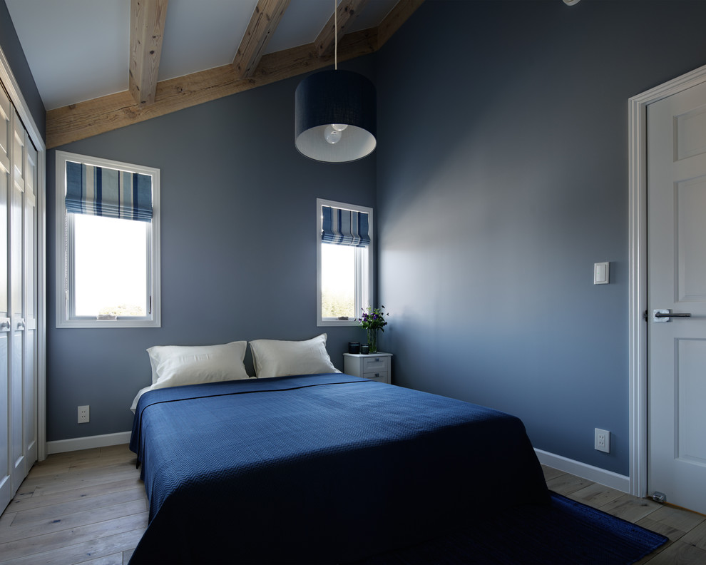 На фото: спальня в скандинавском стиле с синими стенами, светлым паркетным полом и коричневым полом с