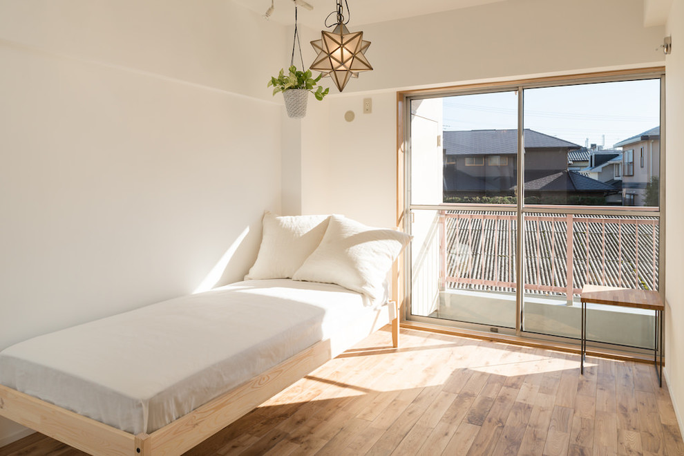Diseño de dormitorio nórdico con paredes blancas y suelo de madera en tonos medios
