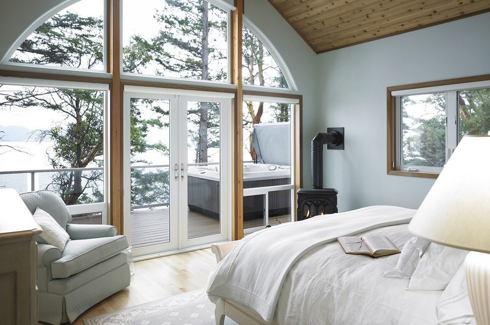 Modelo de dormitorio principal rural con paredes blancas, suelo de madera clara y estufa de leña