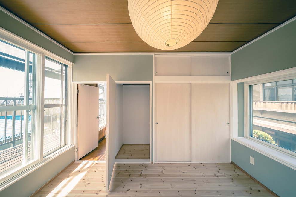 Kleines Nordisches Hauptschlafzimmer ohne Kamin mit hellem Holzboden, grauer Wandfarbe und braunem Boden in Sonstige