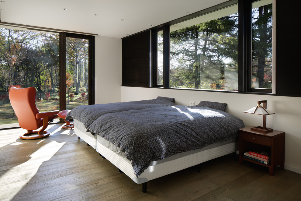 На фото: спальня в современном стиле с белыми стенами, деревянным полом и серым полом