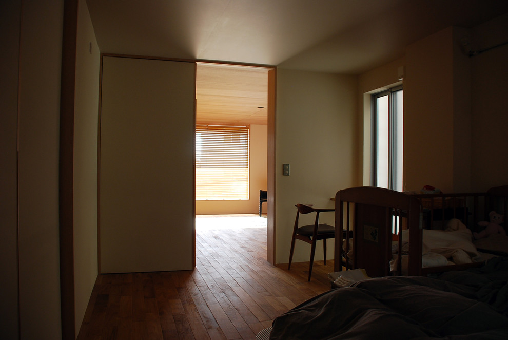 Modelo de dormitorio principal moderno con paredes beige, suelo de madera oscura y suelo marrón