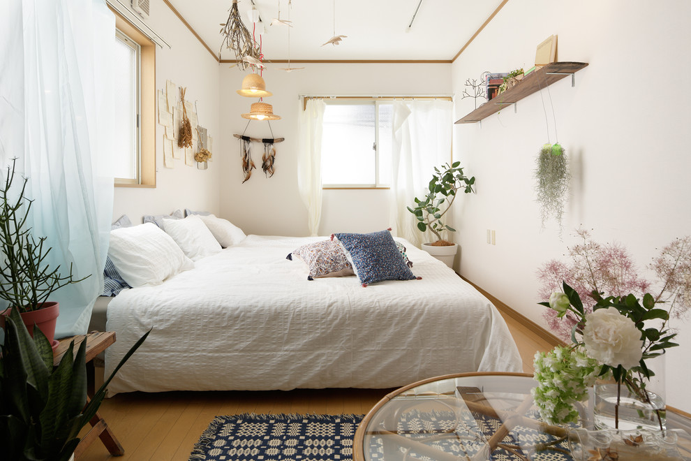 Ejemplo de dormitorio principal campestre grande sin chimenea con paredes blancas y suelo de madera en tonos medios
