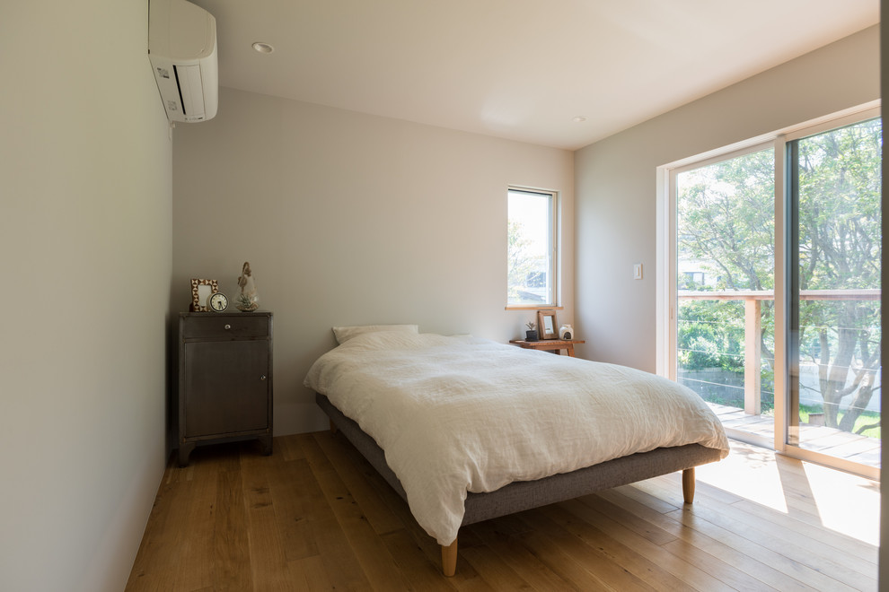 Idee per una camera matrimoniale minimal con pareti grigie, pavimento in legno massello medio e pavimento marrone