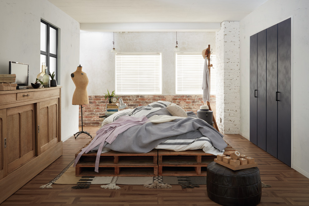 Modelo de dormitorio industrial con paredes blancas, suelo de madera en tonos medios y suelo marrón