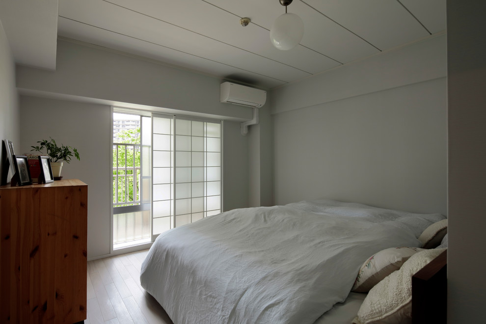 Imagen de dormitorio principal moderno con paredes blancas, suelo de contrachapado y suelo beige