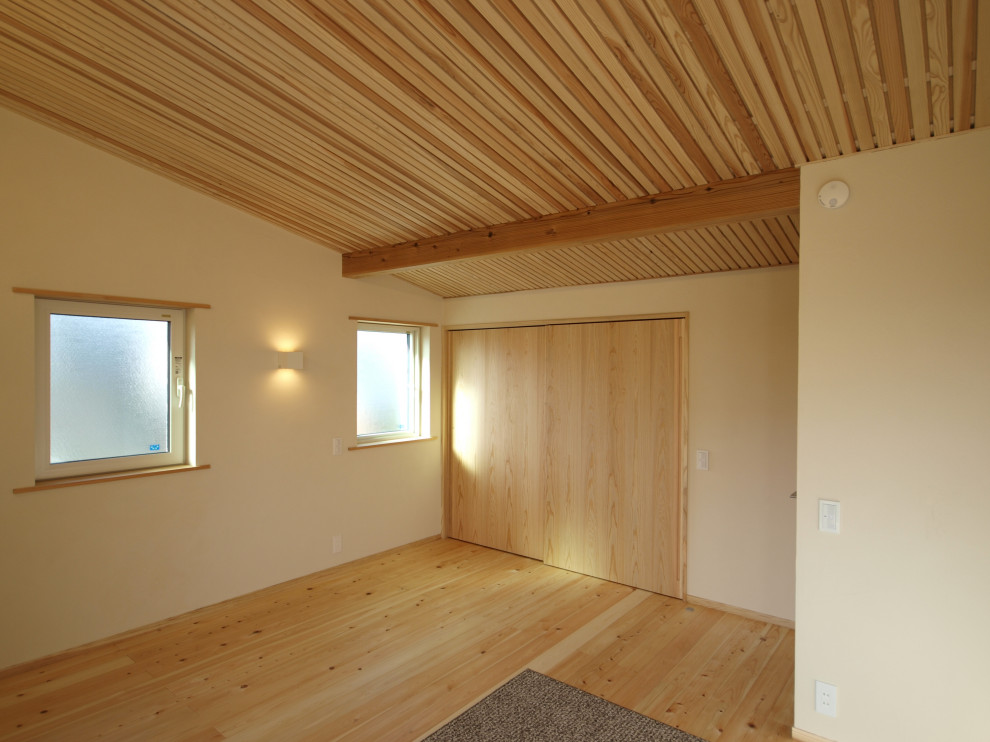 Imagen de dormitorio principal costero con paredes blancas, suelo de madera clara y suelo beige