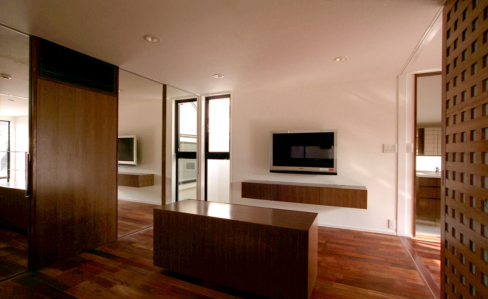 Modelo de dormitorio principal moderno de tamaño medio sin chimenea con paredes blancas, suelo de madera oscura y suelo marrón