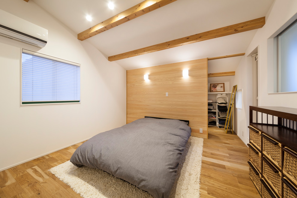This is an example of a world-inspired bedroom in Other with white walls and brown floors.