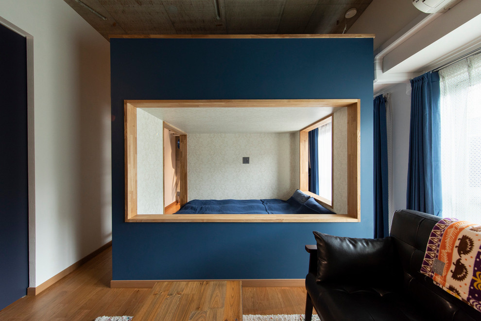 Idee per una camera da letto industriale con pareti blu, pavimento in legno massello medio e nessun camino