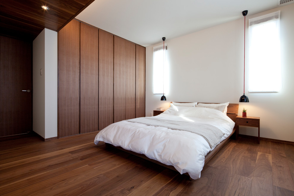 他の地域にある中くらいな北欧スタイルのおしゃれな主寝室 (白い壁、濃色無垢フローリング、茶色い床) のレイアウト