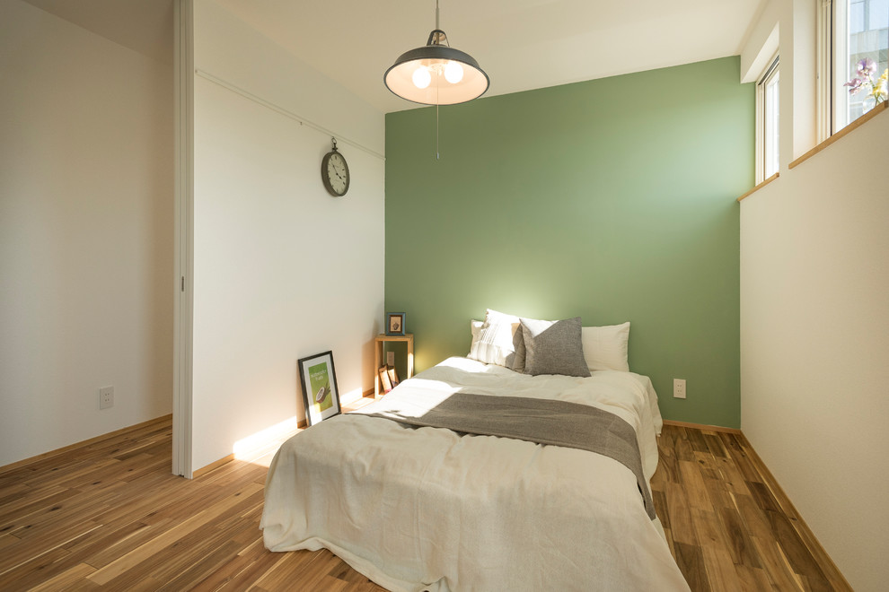 Foto de dormitorio contemporáneo con paredes verdes, suelo de madera en tonos medios y suelo marrón