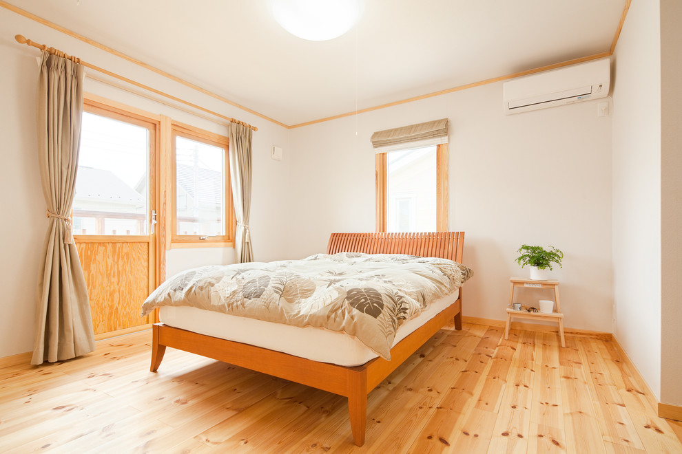Großes Nordisches Schlafzimmer ohne Kamin mit weißer Wandfarbe und hellem Holzboden in Sonstige