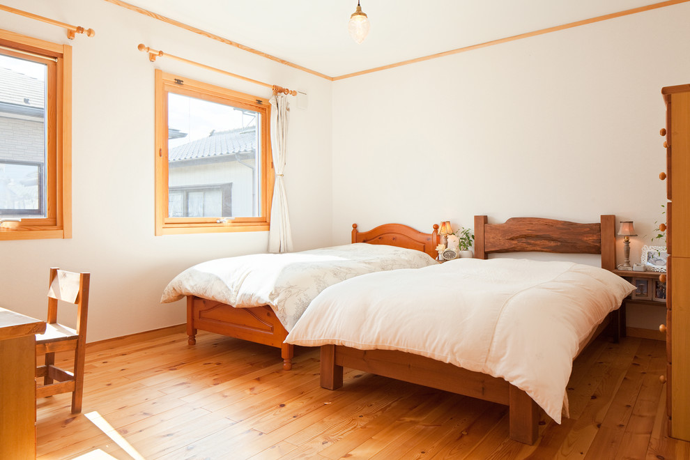 Foto di una camera da letto scandinava di medie dimensioni con pareti bianche, pavimento in legno massello medio e pavimento marrone