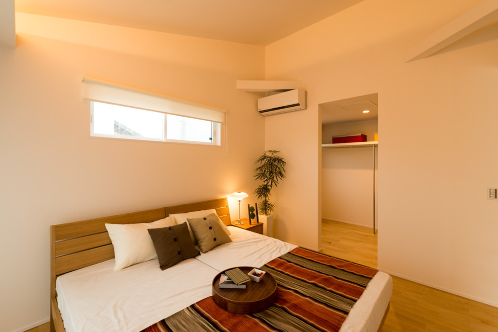 Modernes Schlafzimmer mit weißer Wandfarbe, braunem Holzboden und braunem Boden in Sonstige