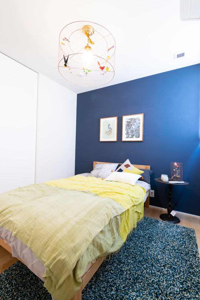 Foto på ett litet minimalistiskt huvudsovrum, med blå väggar, ljust trägolv och brunt golv