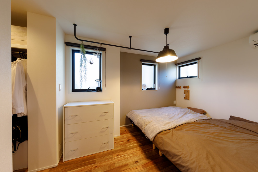 Modelo de dormitorio principal urbano con paredes blancas, suelo de madera en tonos medios y suelo marrón