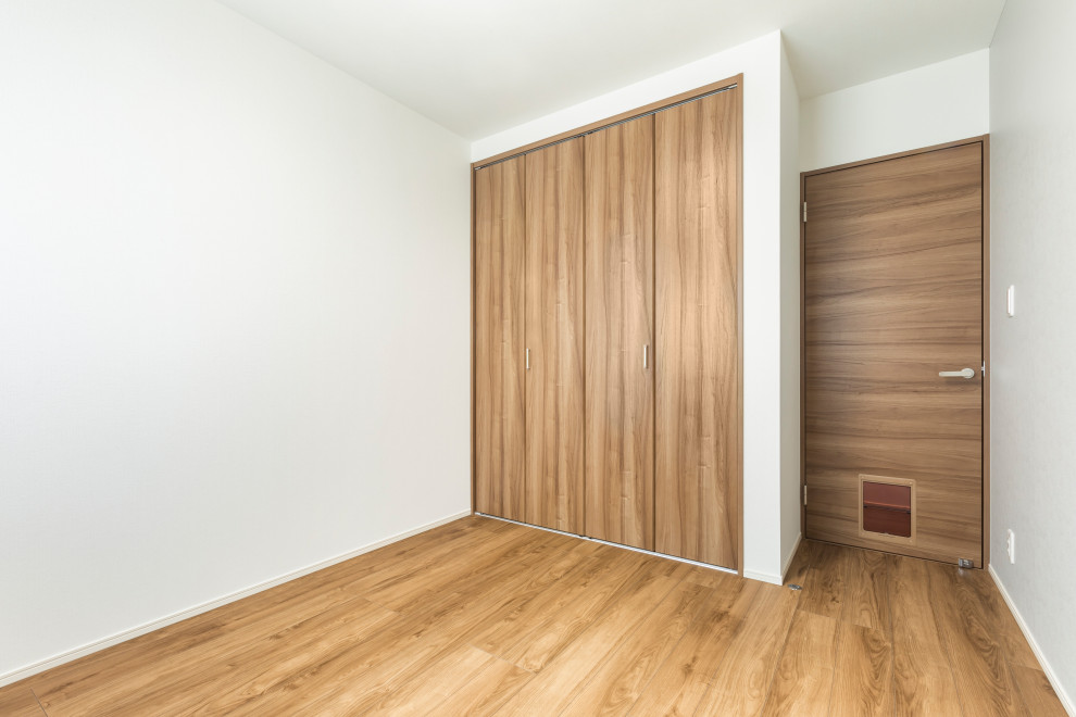 Foto di una camera da letto moderna di medie dimensioni con pareti bianche, pavimento in compensato e pavimento marrone