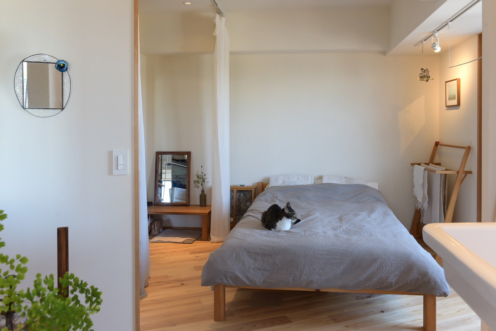 Modelo de dormitorio asiático con paredes blancas, suelo de madera en tonos medios y suelo marrón