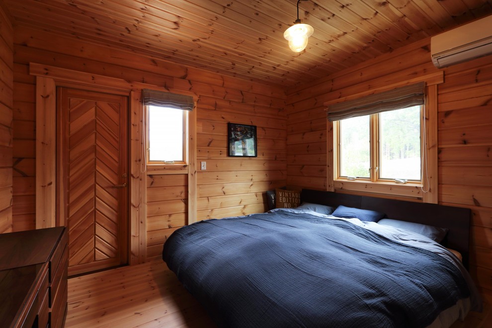 Diseño de dormitorio rústico con paredes marrones, suelo de madera en tonos medios y suelo marrón
