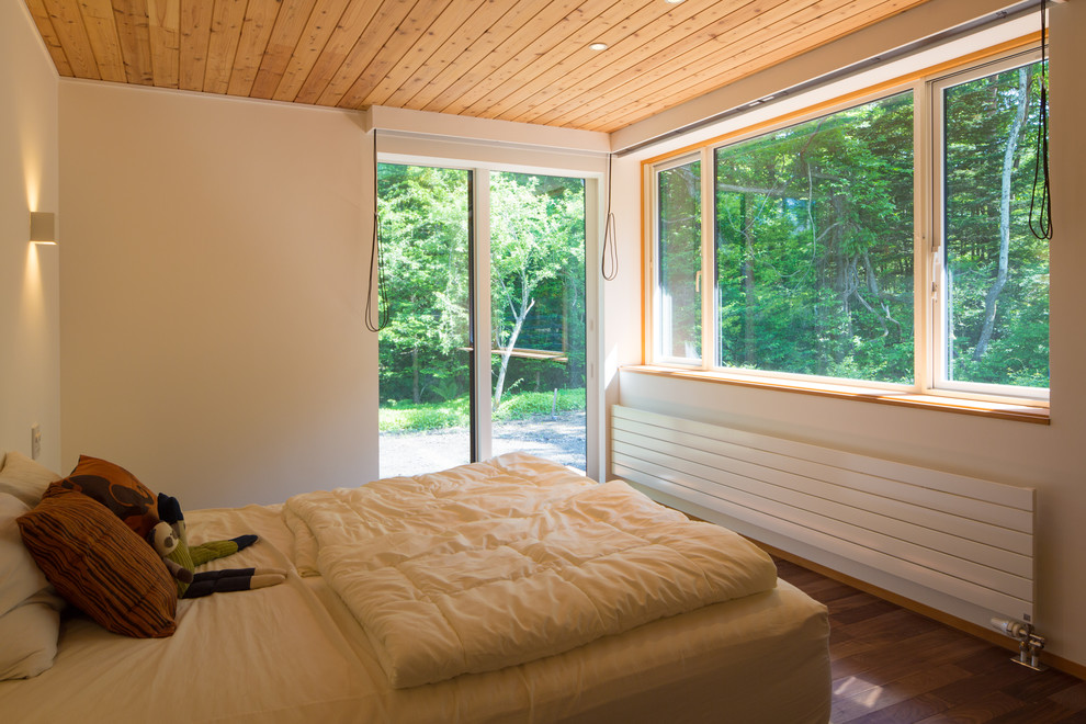 На фото: хозяйская спальня среднего размера в восточном стиле с белыми стенами, темным паркетным полом и коричневым полом без камина с